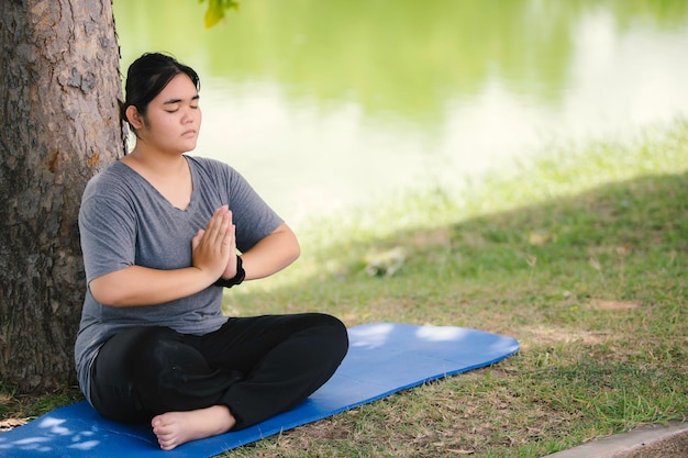 La bella donna grassa asiatica gioca a yoga al parco Necessità di dimagrire il corpo