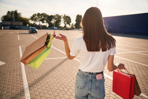 La bella donna in abiti casuali sta tenendo le borse della spesa all'aperto