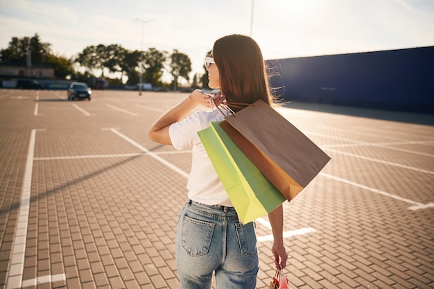 La bella donna in abiti casuali sta tenendo le borse della spesa all'aperto