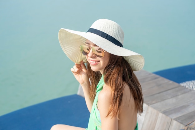 La bella donna in cappello bianco sta sedendosi sull&#39;hotel con la spiaggia