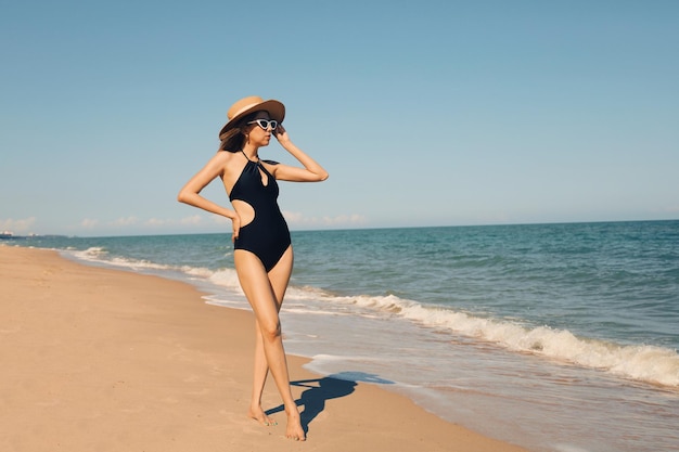 La bella donna in costume da bagno sexy viaggia sulla spiaggia tropicale