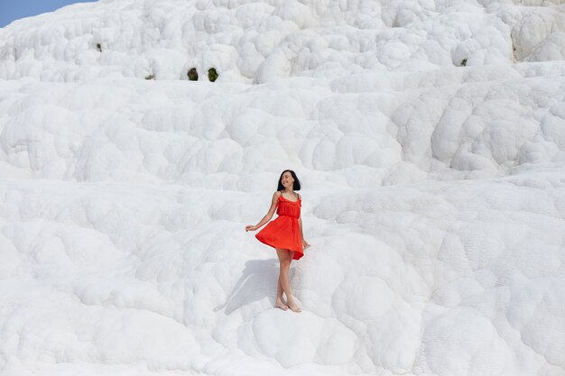 La bella donna in un vestito rosso sta contro le montagne bianche.