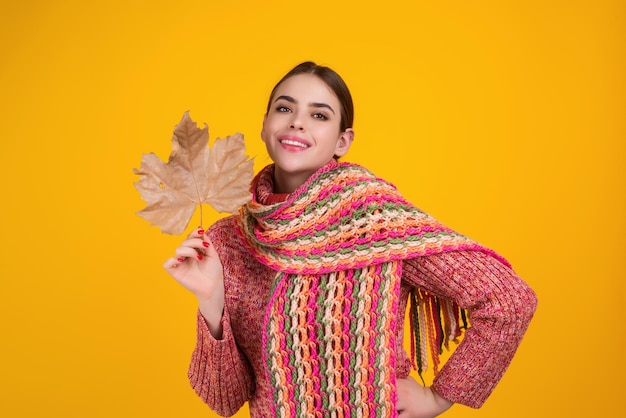 La bella donna in vestiti di autunno tiene le foglie che cadono che posano nello studio splendida ragazza modella bruna