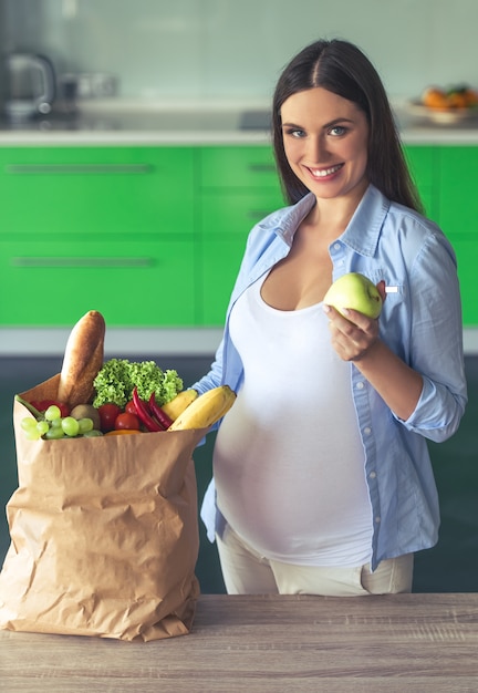 La bella donna incinta sta tenendo una mela.