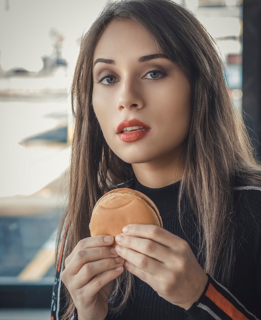 La bella donna mangia un hamburger