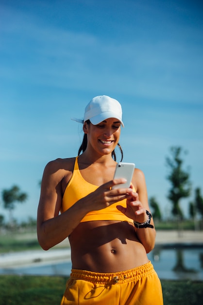 La bella donna si è vestita negli sport facendo uso del telefono cellulare mobile.