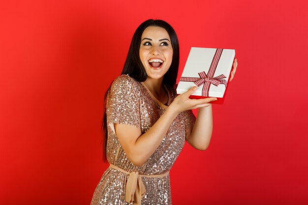 La bella donna sorridente sta cercando di indovinare cosa c'è dentro la confezione regalo.