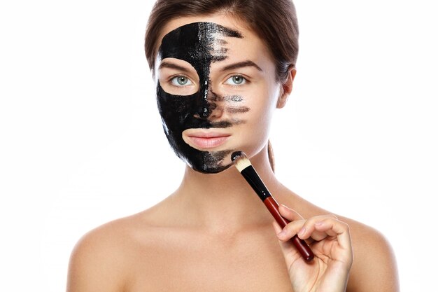 La bella donna sta applicando la maschera nera purificante sul suo fronte