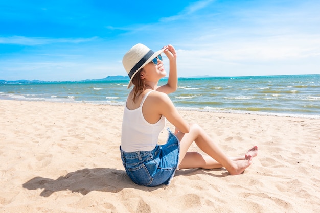 La bella donna sta sedendosi sulla spiaggia