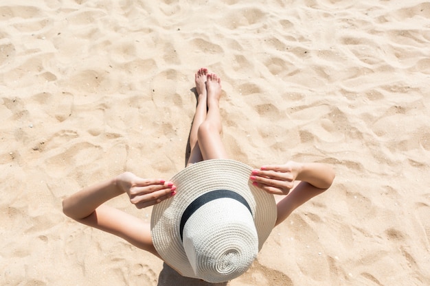 La bella donna sta sedendosi sulla spiaggia