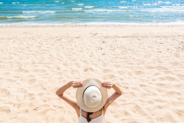 La bella donna sta sedendosi sulla spiaggia