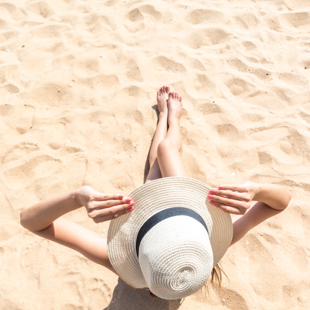 La bella donna sta sedendosi sulla spiaggia