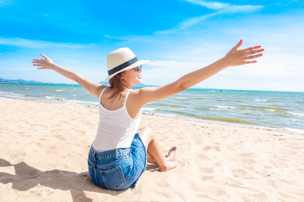 La bella donna sta sedendosi sulla spiaggia