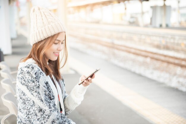 La bella donna sta utilizzando lo Smart Phone sulla piattaforma ferroviaria