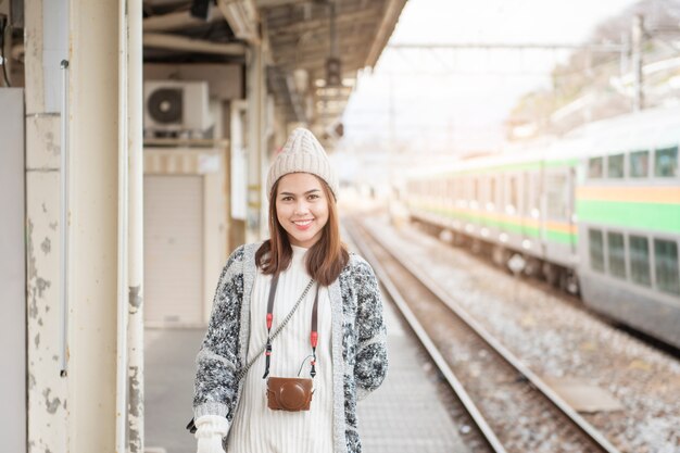 La bella donna turistica sta stando sulla piattaforma ferroviaria con la sua mappa