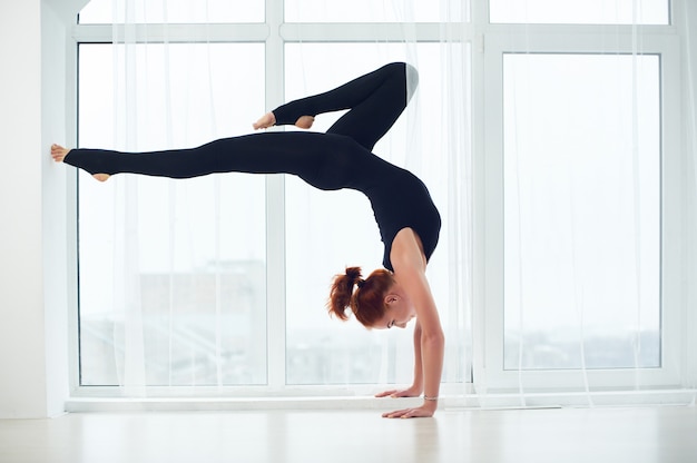 La bella donna yogi in forma sportiva pratica asana di yoga Bhuja Vrischikasana