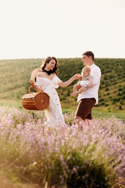 La bella e giovane famiglia in un campo di lavanda trascorre la giornata