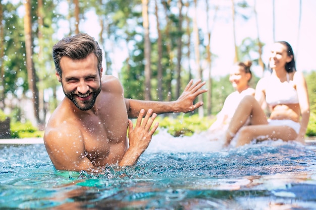 La bella famiglia moderna eccitata e felice si diverte in piscina durante le vacanze estive.