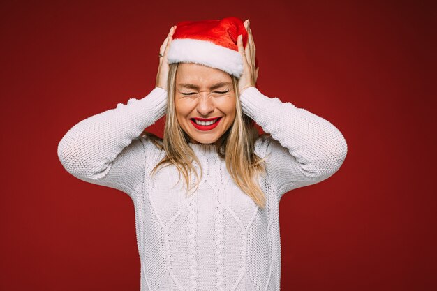 La bella femmina caucasica in maglione bianco e cappello di natale non vuole sentire qualcosa