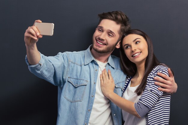 La bella giovane coppia in abbigliamento casual sta facendo un selfie.