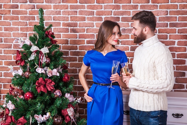 La bella giovane coppia sta celebrando il natale a casa si guarda negli occhi e sorride