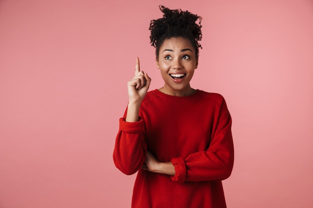 la bella giovane donna africana emozionale felice emozionante che posa isolata sopra la parete rosa che indica ha un'idea.