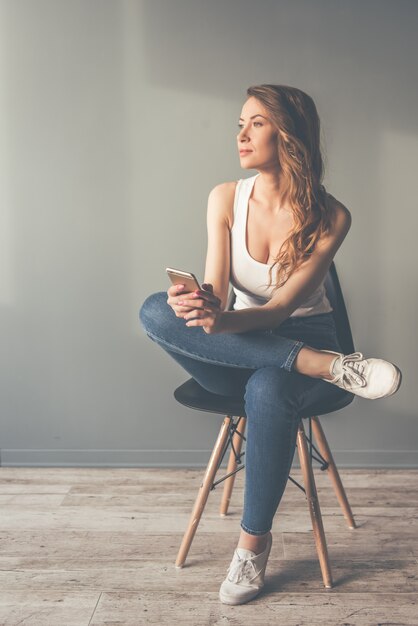 La bella giovane donna alla moda sta tenendo uno smartphone