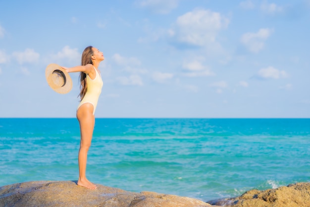 La bella giovane donna asiatica del ritratto si rilassa il tempo libero di sorriso intorno all'oceano del mare della spiaggia sul viaggio di vacanza di viaggio