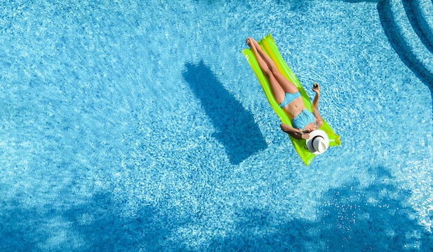 La bella giovane donna che si rilassa nella ragazza della piscina nuota sul materasso gonfiabile e si diverte io