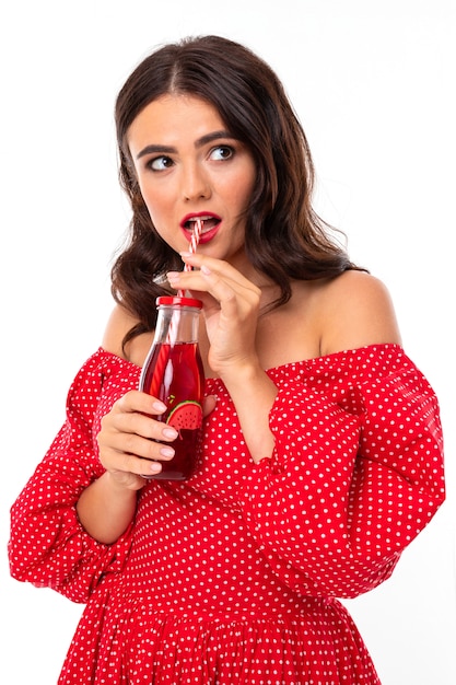 La bella giovane donna con il sorriso perfetto beve il succo di fragola isolato