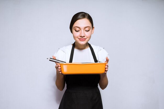 La bella giovane donna cucina in un grembiule nero che prepara una torta deliziosa, godendosi l'aroma