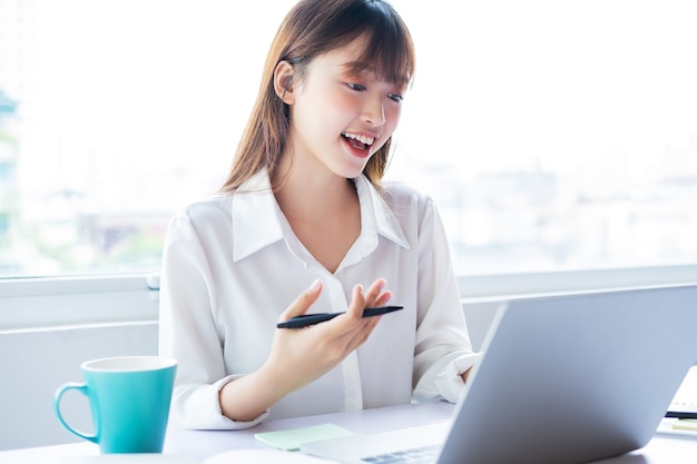 La bella giovane donna d'affari asiatica sta lavorando online con un buon umore