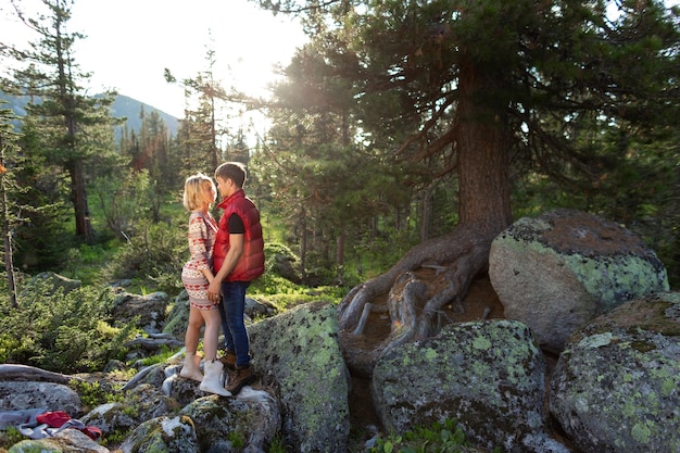 La bella giovane donna e l'uomo camminano abbracciati e baciati nella natura di montagna al tramonto