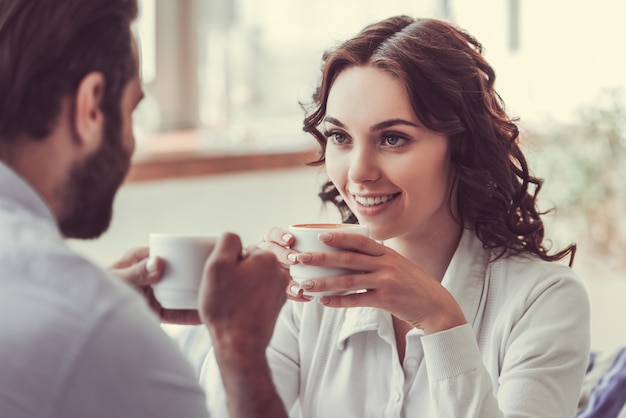 La bella giovane donna e l'uomo nell'amore stanno bevendo il caffè.