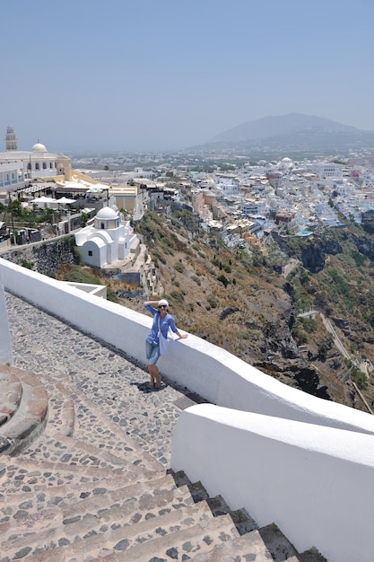 La bella giovane donna greca in abiti di moda si diverte a n le strade di Oia, Santorini, Grecia