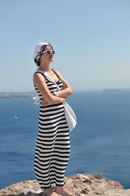 La bella giovane donna greca in abiti di moda si diverte a n le strade di Oia, Santorini, Grecia