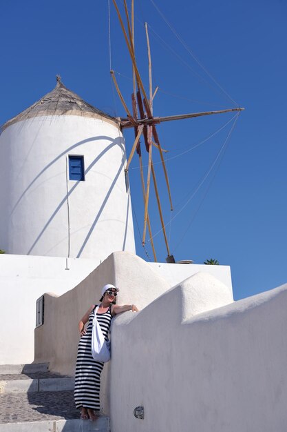 La bella giovane donna greca in abiti di moda si diverte a n le strade di Oia, Santorini, Grecia