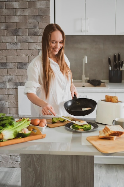 La bella giovane donna nella cucina a casa prepara l'alimento sano