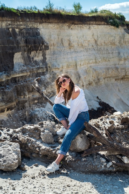 La bella giovane donna sexy posa i vestiti casuali sulla cava di sabbia. all'aperto