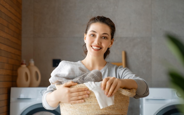 La bella giovane donna sorride mentre fa il bucato a casa