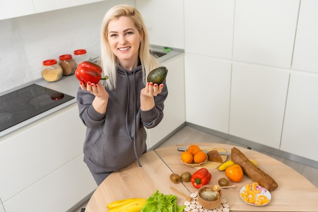 La bella giovane donna sta preparando l'insalata di verdure in cucina. Cucinare a casa.