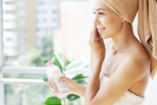 La bella giovane donna sta pulendo il viso usando un disco di cotone