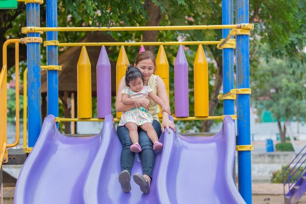 La bella giovane madre gioca con tua figlia divertendosi al parco giochiBuon giorno della mammaLa gente della Thailandia