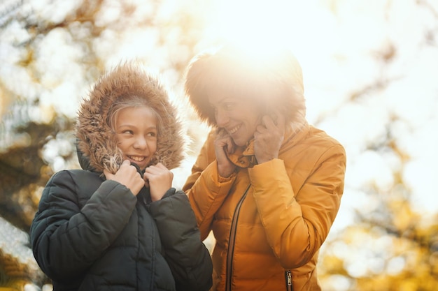 La bella madre e la sua felice figlia adolescente sorridono e si divertono nel parco al tramonto.