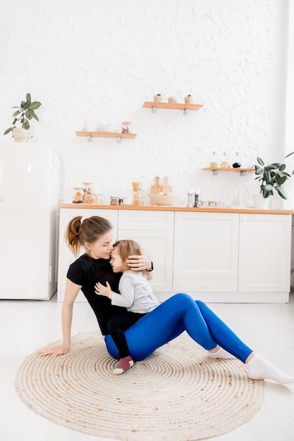 La bella madre sorridente fa sport con sua figlia a casa