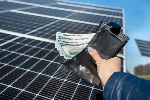 La bella mano femminile tiene il portafoglio nero con banconote da un dollaro che tiene vicino al sole