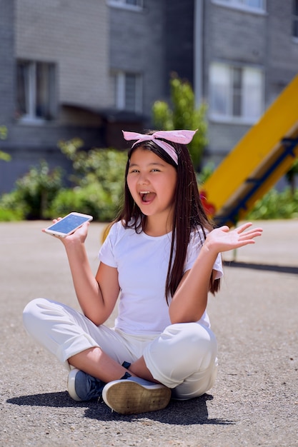 La bella piccola ragazza asiatica con il telefono sulla strada è sorpresa