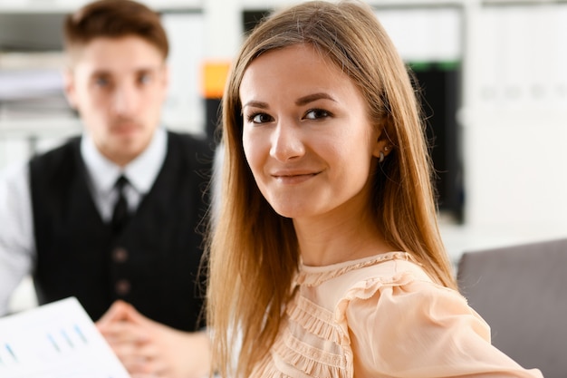 La bella ragazza allegra sorridente sul posto di lavoro guarda a porte chiuse