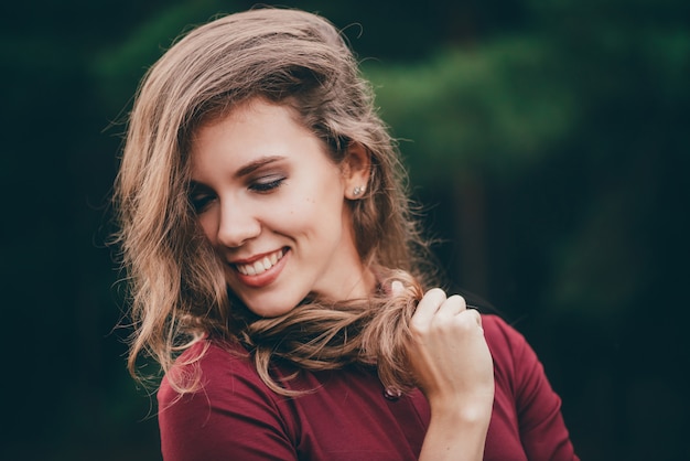 La bella ragazza con capelli naturali ricci ride in foresta.