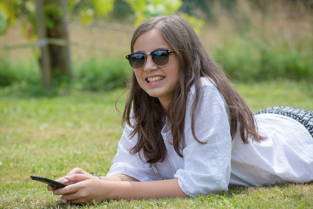 La bella ragazza con gli occhiali da sole sta usando lo smartphone